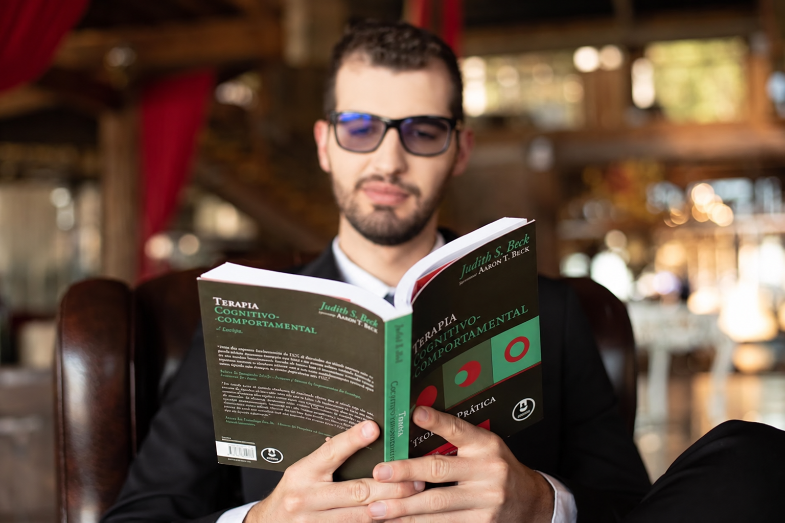 Psicólogo Tiago Ribeiro lendo um livro sobre Terapia Cognitivo-Comportamental